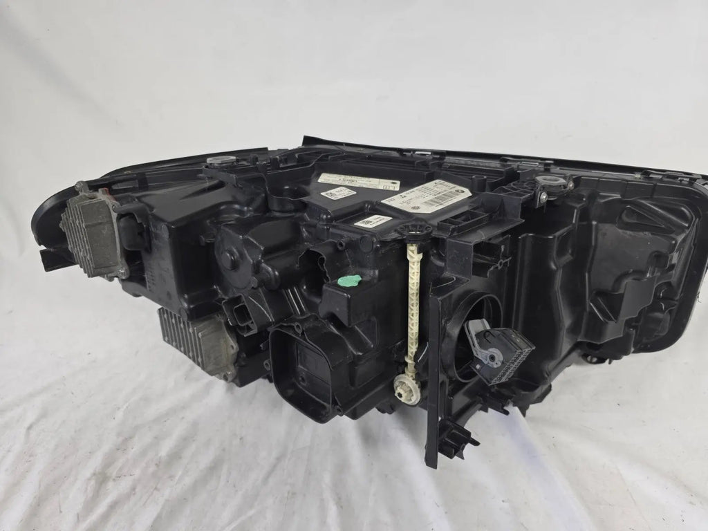 Genuine OEM BMW Laser headlight for 5 Series models G30, G31, and F90 LCI (facelift). This left-side headlamp, part number 5A388D5, is equipped with advanced laser lighting technology for superior visibility and precision on the road. The image displays the original left laser headlight in used condition, clearly showing the lens structure, cooling fins, mounting points, and connector ports — ideal for OEM replacement on compatible BMW 5 Series LCI vehicles.