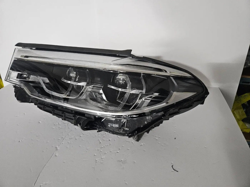 This image shows the left-side Adaptive LED ICON headlight for the BMW 5 Series G30, G31, G38, and F90 LCI models, featuring OEM genuine quality with part number 8499121. This used original headlamp is designed for the facelifted (LCI) versions of these models, offering BMW’s signature Adaptive LED ICON lighting technology for enhanced visibility, precise beam control, and a sleek, modern design.
