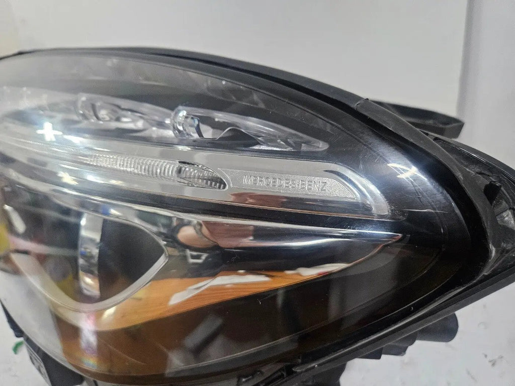 Genuine used Mercedes-Benz Bi-Xenon headlight for GLA-Class model X156. This left-side (LH) OEM headlamp, part number A1569061700, features Bi-Xenon lighting technology for enhanced night visibility and a focused beam pattern. The image shows the original left headlight in used condition, highlighting the lens clarity, projector unit, mounting brackets, and electrical connector — ideal for replacing a damaged headlamp on compatible Mercedes-Benz GLA X156 vehicles.