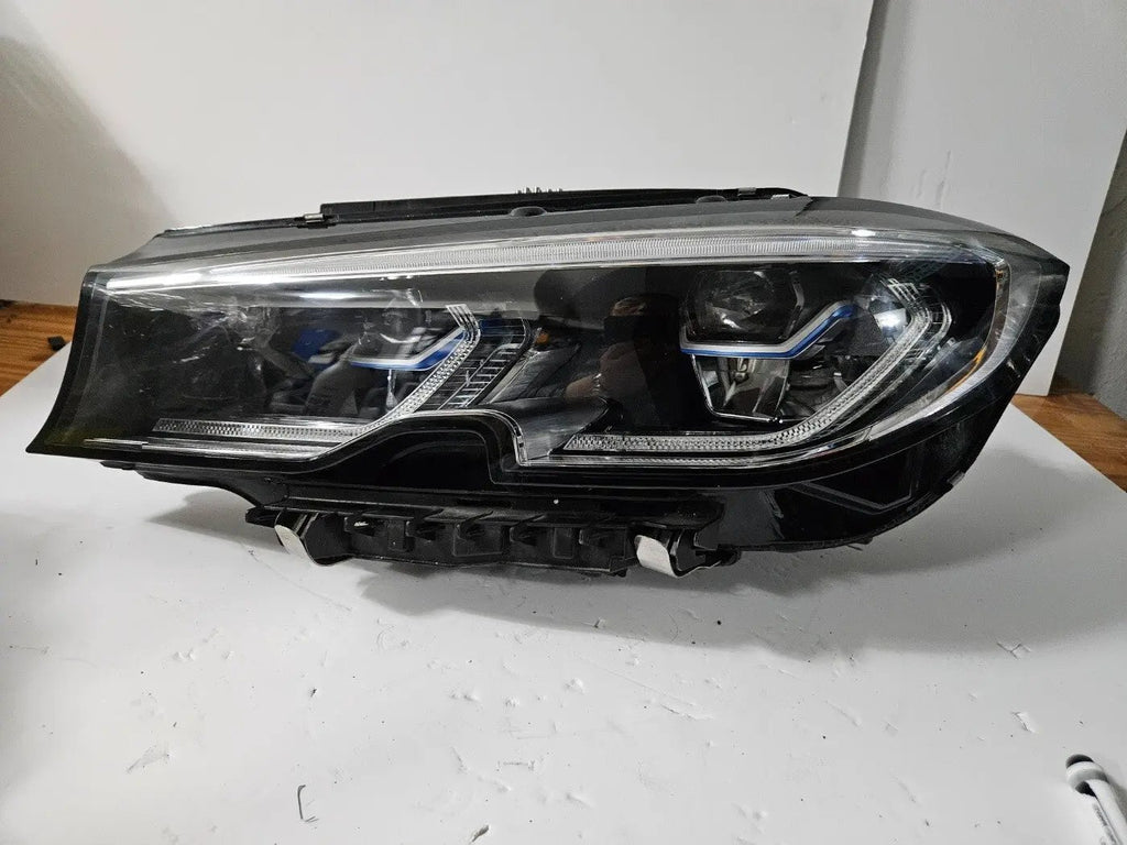 Genuine used BMW Laser headlight for 3 Series models G20 and G21. This left-side OEM headlamp, part number 9481707, features high-performance laser lighting technology for superior road visibility and driving precision. The image showcases the original left laser headlight in used condition, clearly showing the lens structure, housing, and connector ports β ideal for replacing a damaged headlamp on compatible BMW 3 Series vehicles.