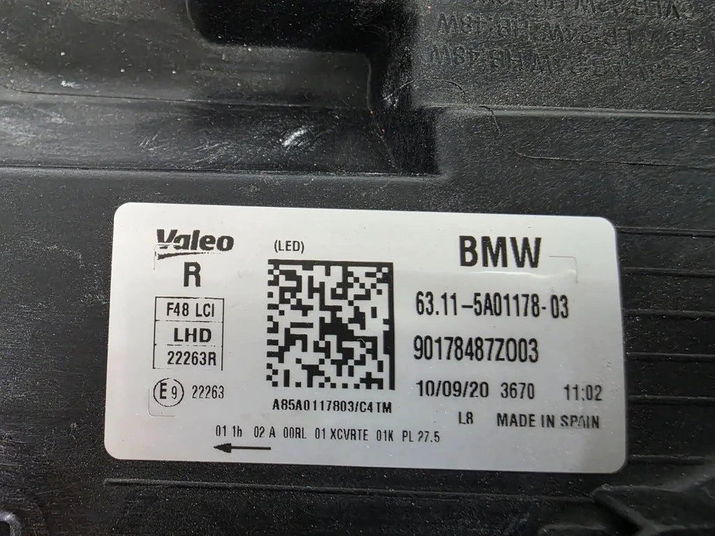 Used genuine BMW Adaptive LED headlight for X1 F48 LCI (facelift) model. This right-side OEM headlamp, part number 5A01178, is equipped with adaptive lighting technology for improved night visibility and cornering performance. The image displays the original right Adaptive LED headlight in used condition, showing the clear lens, mounting brackets, and electrical connectors — an ideal OEM replacement for BMW X1 F48 LCI vehicles.