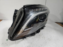 Load image into Gallery viewer, Genuine used Mercedes-Benz Bi-Xenon headlight for GLA-Class model X156. This left-side (LH) OEM headlamp, part number A1569061700, features Bi-Xenon lighting technology for enhanced night visibility and a focused beam pattern. The image shows the original left headlight in used condition, highlighting the lens clarity, projector unit, mounting brackets, and electrical connector — ideal for replacing a damaged headlamp on compatible Mercedes-Benz GLA X156 vehicles.