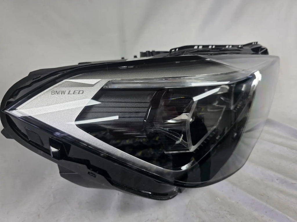Used genuine BMW Adaptive LED headlight for X1 F48 LCI (facelift) model. This right-side OEM headlamp, part number 5A01178, is equipped with adaptive lighting technology for improved night visibility and cornering performance. The image displays the original right Adaptive LED headlight in used condition, showing the clear lens, mounting brackets, and electrical connectors — an ideal OEM replacement for BMW X1 F48 LCI vehicles.