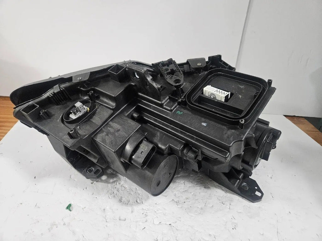 Genuine used Mercedes-Benz Bi-Xenon headlight for GLA-Class model X156. This left-side (LH) OEM headlamp, part number A1569061700, features Bi-Xenon lighting technology for enhanced night visibility and a focused beam pattern. The image shows the original left headlight in used condition, highlighting the lens clarity, projector unit, mounting brackets, and electrical connector — ideal for replacing a damaged headlamp on compatible Mercedes-Benz GLA X156 vehicles.