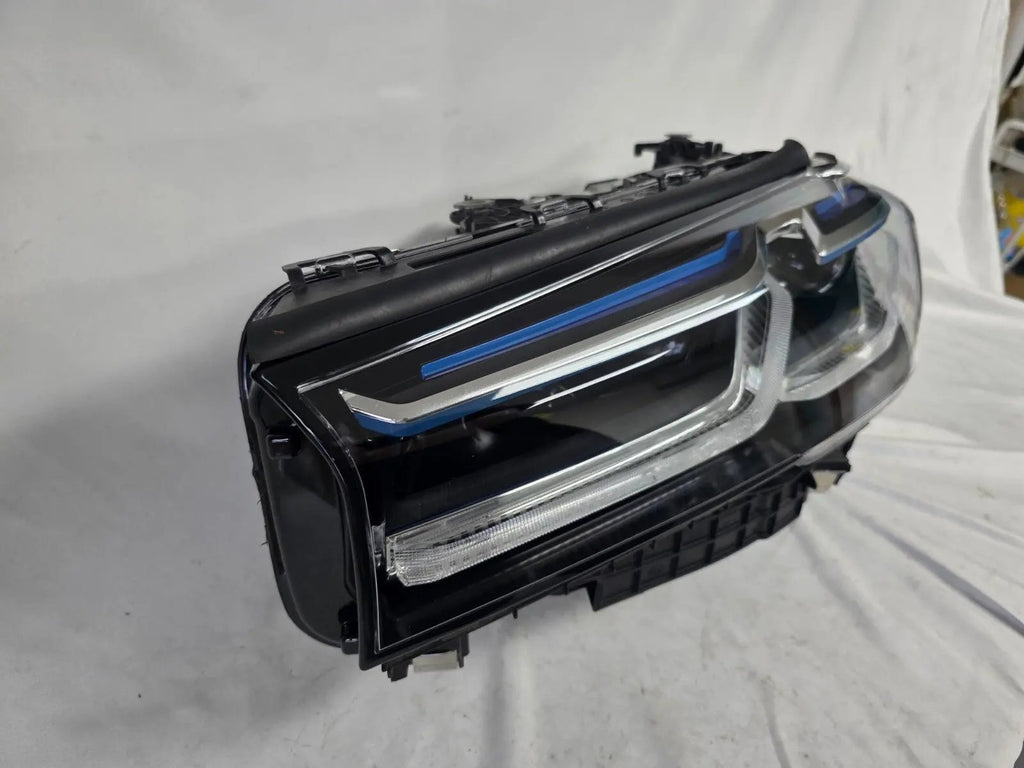 Genuine OEM BMW Laser headlight for 5 Series models G30, G31, and F90 LCI (facelift). This left-side headlamp, part number 5A388D5, is equipped with advanced laser lighting technology for superior visibility and precision on the road. The image displays the original left laser headlight in used condition, clearly showing the lens structure, cooling fins, mounting points, and connector ports — ideal for OEM replacement on compatible BMW 5 Series LCI vehicles.