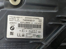 Load image into Gallery viewer, Used genuine BMW Laser headlight for 7 Series models G11 and G12. This right-side OEM headlamp, part number 7465606, features advanced laser lighting technology for superior visibility and performance. The image shows the original BMW right laser headlight in used condition, highlighting the detailed lens design, housing structure, and connector ports — ideal for high-end replacement or repair on compatible 7 Series vehicles.