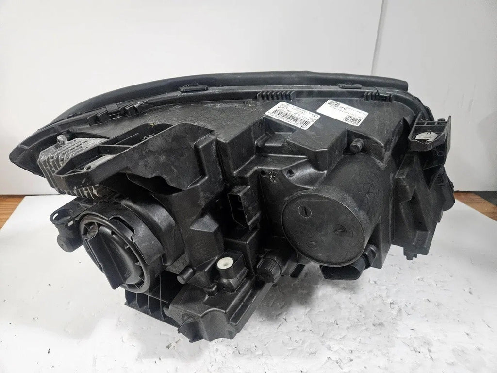 Genuine used Mercedes-Benz Bi-Xenon headlight for GLA-Class model X156. This left-side (LH) OEM headlamp, part number A1569061700, features Bi-Xenon lighting technology for enhanced night visibility and a focused beam pattern. The image shows the original left headlight in used condition, highlighting the lens clarity, projector unit, mounting brackets, and electrical connector — ideal for replacing a damaged headlamp on compatible Mercedes-Benz GLA X156 vehicles.