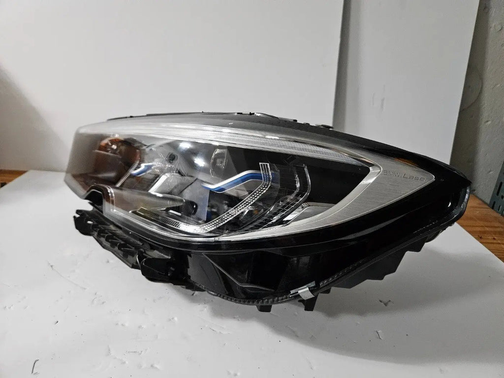 Genuine used BMW Laser headlight for 3 Series models G20 and G21. This left-side OEM headlamp, part number 9481707, features high-performance laser lighting technology for superior road visibility and driving precision. The image showcases the original left laser headlight in used condition, clearly showing the lens structure, housing, and connector ports β ideal for replacing a damaged headlamp on compatible BMW 3 Series vehicles.