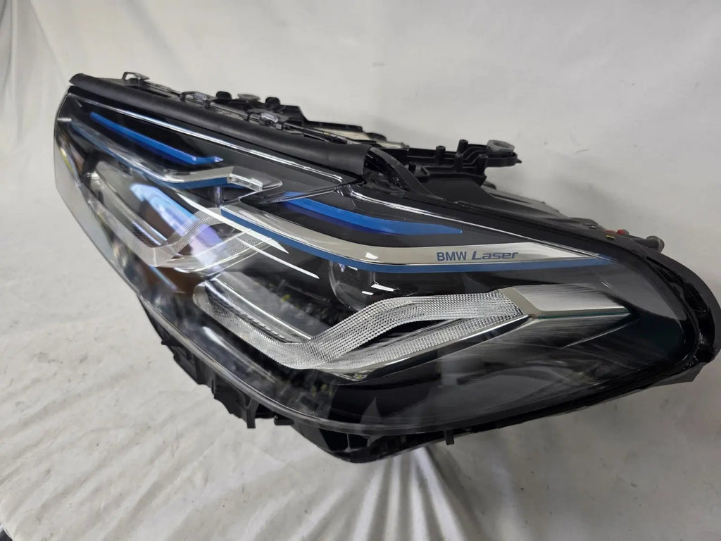 Genuine OEM BMW Laser headlight for 5 Series models G30, G31, and F90 LCI (facelift). This left-side headlamp, part number 5A388D5, is equipped with advanced laser lighting technology for superior visibility and precision on the road. The image displays the original left laser headlight in used condition, clearly showing the lens structure, cooling fins, mounting points, and connector ports — ideal for OEM replacement on compatible BMW 5 Series LCI vehicles.