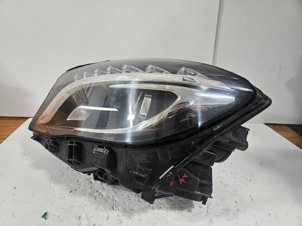Genuine used Mercedes-Benz Bi-Xenon headlight for GLA-Class model X156. This left-side (LH) OEM headlamp, part number A1569061700, features Bi-Xenon lighting technology for enhanced night visibility and a focused beam pattern. The image shows the original left headlight in used condition, highlighting the lens clarity, projector unit, mounting brackets, and electrical connector — ideal for replacing a damaged headlamp on compatible Mercedes-Benz GLA X156 vehicles.