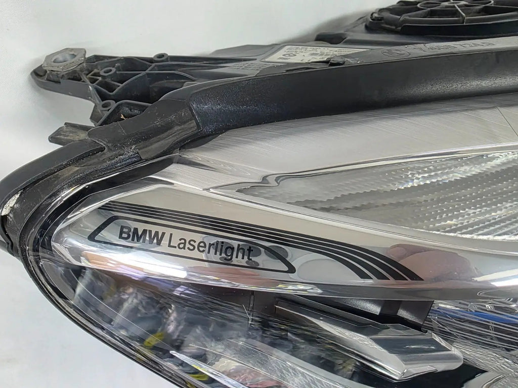 Used genuine BMW Laser headlight for 7 Series models G11 and G12. This right-side OEM headlamp, part number 7465606, features advanced laser lighting technology for superior visibility and performance. The image shows the original BMW right laser headlight in used condition, highlighting the detailed lens design, housing structure, and connector ports — ideal for high-end replacement or repair on compatible 7 Series vehicles.