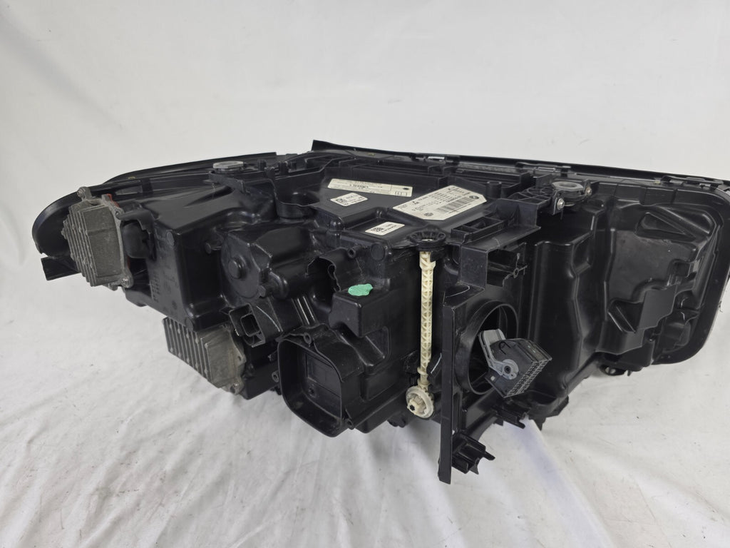 Genuine OEM BMW Laser headlight for 5 Series models G30, G31, and F90 LCI (facelift). This left-side headlamp, part number 5A388D5, is equipped with advanced laser lighting technology for superior visibility and precision on the road. The image displays the original left laser headlight in used condition, clearly showing the lens structure, cooling fins, mounting points, and connector ports — ideal for OEM replacement on compatible BMW 5 Series LCI vehicles.

