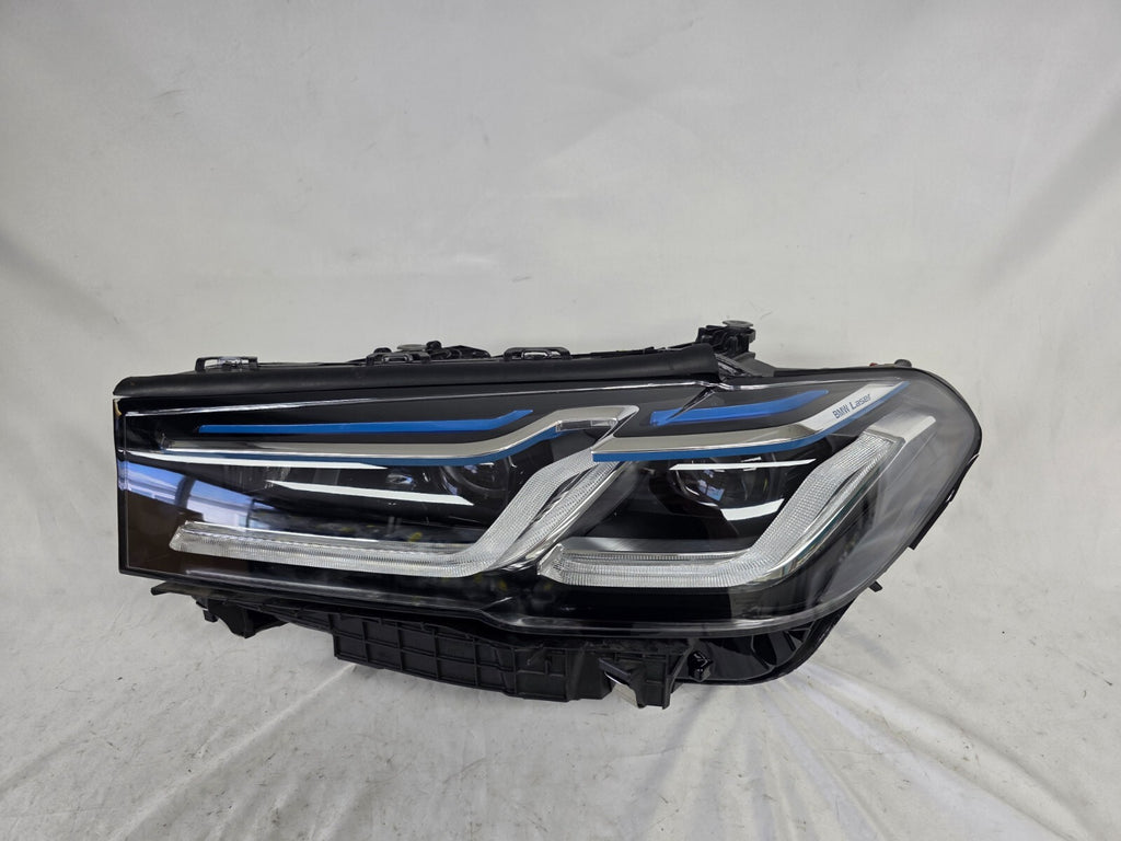 Genuine OEM BMW Laser headlight for 5 Series models G30, G31, and F90 LCI (facelift). This left-side headlamp, part number 5A388D5, is equipped with advanced laser lighting technology for superior visibility and precision on the road. The image displays the original left laser headlight in used condition, clearly showing the lens structure, cooling fins, mounting points, and connector ports — ideal for OEM replacement on compatible BMW 5 Series LCI vehicles.

