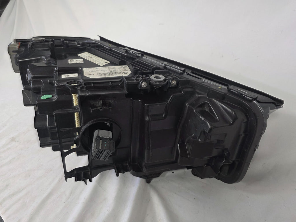Genuine OEM BMW Laser headlight for 5 Series models G30, G31, and F90 LCI (facelift). This left-side headlamp, part number 5A388D5, is equipped with advanced laser lighting technology for superior visibility and precision on the road. The image displays the original left laser headlight in used condition, clearly showing the lens structure, cooling fins, mounting points, and connector ports — ideal for OEM replacement on compatible BMW 5 Series LCI vehicles.

