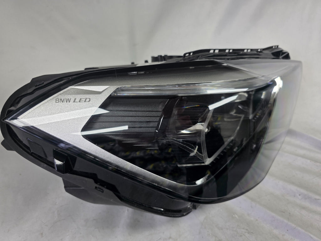 Used genuine BMW Adaptive LED headlight for X1 F48 LCI (facelift) model. This right-side OEM headlamp, part number 5A01178, is equipped with adaptive lighting technology for improved night visibility and cornering performance. The image displays the original right Adaptive LED headlight in used condition, showing the clear lens, mounting brackets, and electrical connectors — an ideal OEM replacement for BMW X1 F48 LCI vehicles.

