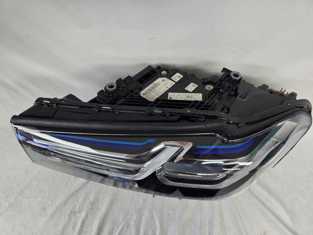 Genuine OEM BMW Laser headlight for 5 Series models G30, G31, and F90 LCI (facelift). This left-side headlamp, part number 5A388D5, is equipped with advanced laser lighting technology for superior visibility and precision on the road. The image displays the original left laser headlight in used condition, clearly showing the lens structure, cooling fins, mounting points, and connector ports — ideal for OEM replacement on compatible BMW 5 Series LCI vehicles.


