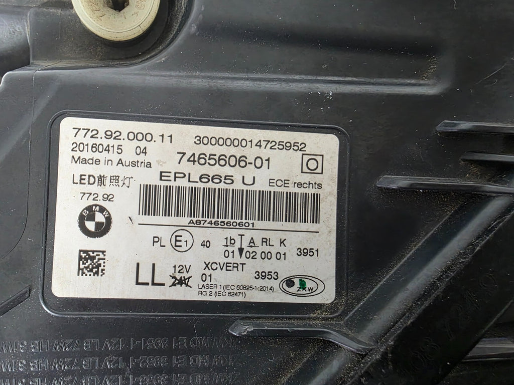Used genuine BMW Laser headlight for 7 Series models G11 and G12. This right-side OEM headlamp, part number 7465606, features advanced laser lighting technology for superior visibility and performance. The image shows the original BMW right laser headlight in used condition, highlighting the detailed lens design, housing structure, and connector ports — ideal for high-end replacement or repair on compatible 7 Series vehicles.


