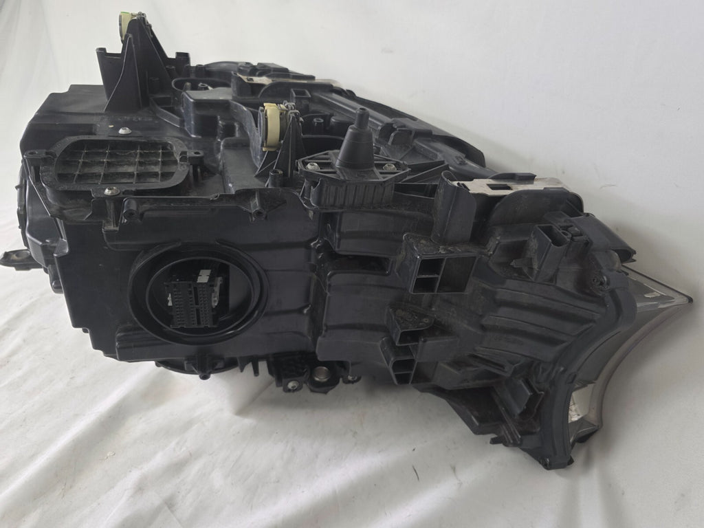 Used genuine BMW Laser headlight for 7 Series models G11 and G12. This right-side OEM headlamp, part number 7465606, features advanced laser lighting technology for superior visibility and performance. The image shows the original BMW right laser headlight in used condition, highlighting the detailed lens design, housing structure, and connector ports — ideal for high-end replacement or repair on compatible 7 Series vehicles.

